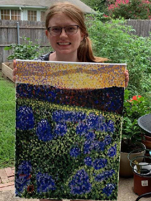 A young woman holding her bluebonnets painting